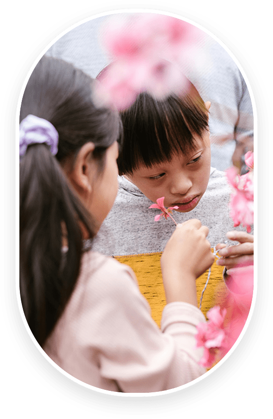 A young girl holding onto a flower while another looks on.