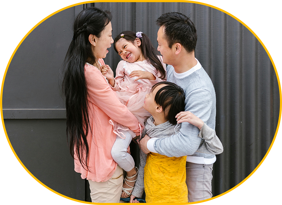 A family of four standing together and smiling.