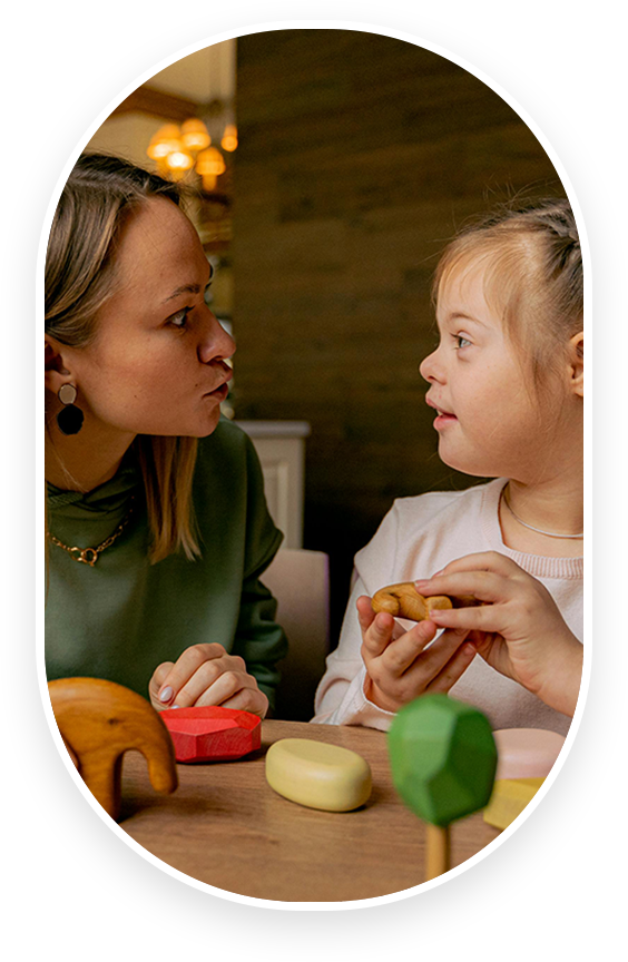 A woman and girl sitting at a table with food.